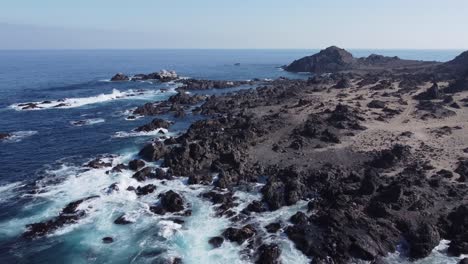 low aerial flyover: jagged shore rocks on arid pacific coast of chile