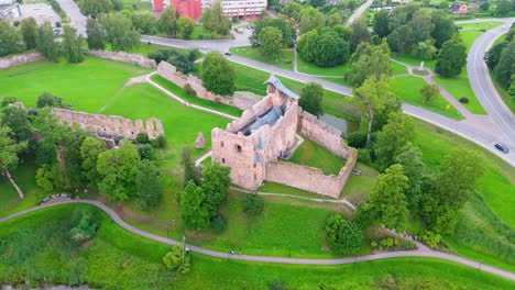 aerial view of dobele castle ruins, flowing berze river and illuminated fountains at sunset serene latvian summer evening from above, scenic aerial of latvian historical landscape in golden hour