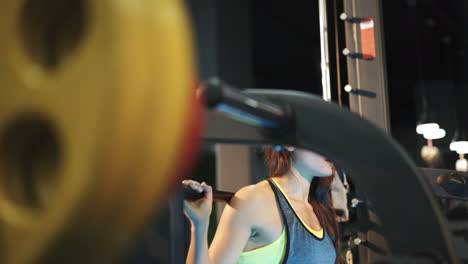 Fitness woman doing sit-ups with a barbell in the gym. Smith's machine in the gym. The ideal female figure. Fitness is the concept of a healthy lifestyle.