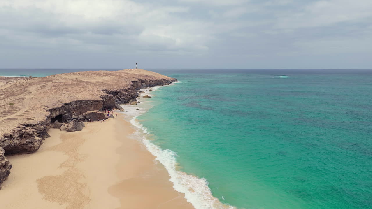 Aerial shot of Varandinha shore,beach is divided by rocks that outline its contour creating a wonderful landscape,in the end of the rocks there a lighthouse,Boa Vista,Cape Verde