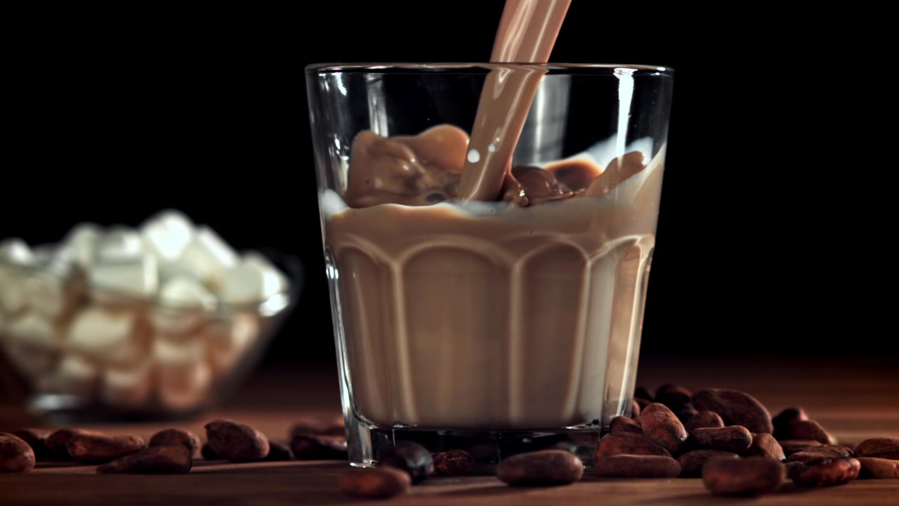 Squisito latte al cioccolato versato in un bicchiere al rallentatore