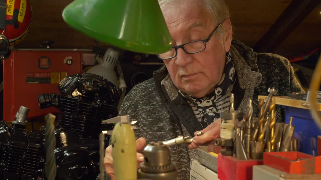 수석 기계공은 워크에서 금속 부품을 측정하기 위해 베르니에 칼리퍼를 사용합니다.