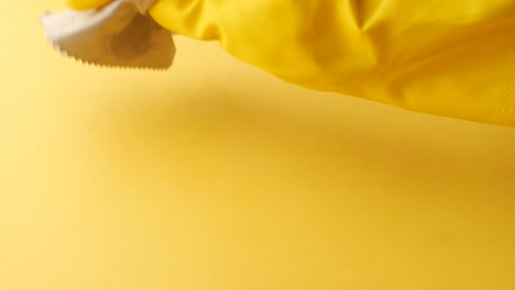 primer plano de una mano con guante limpiando una superficie amarilla