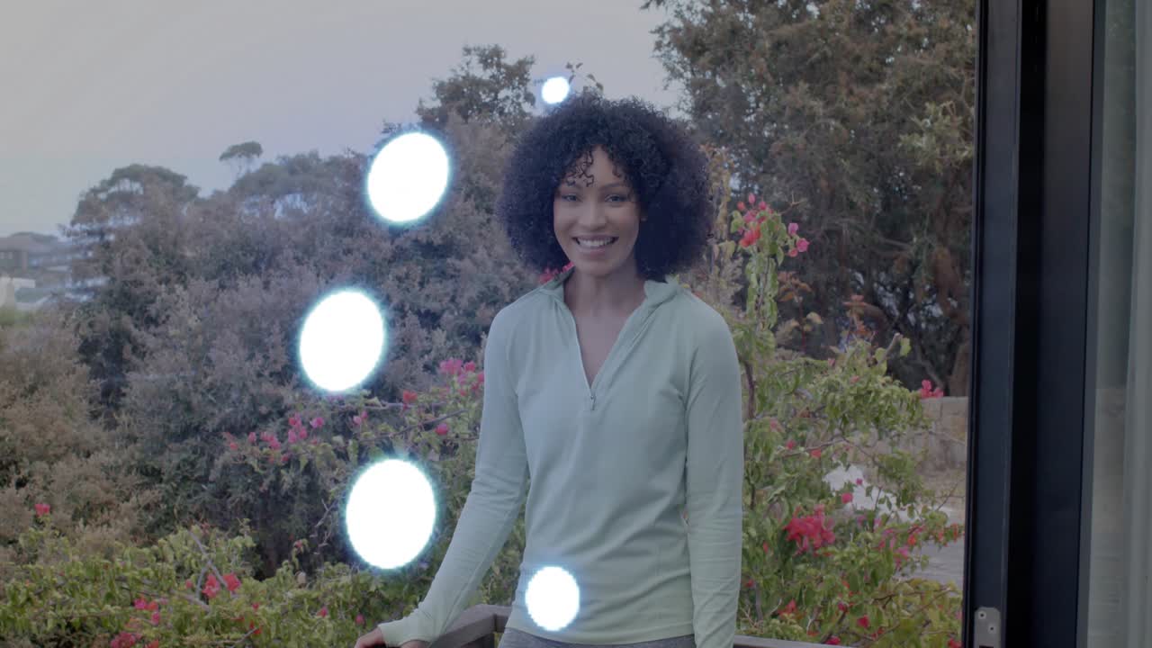 Adult woman standing on balcony, reflections appearing on glass, smiling and laughing for property