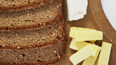 Variety-of-cheese-with-brown-bread-on-wooden-board