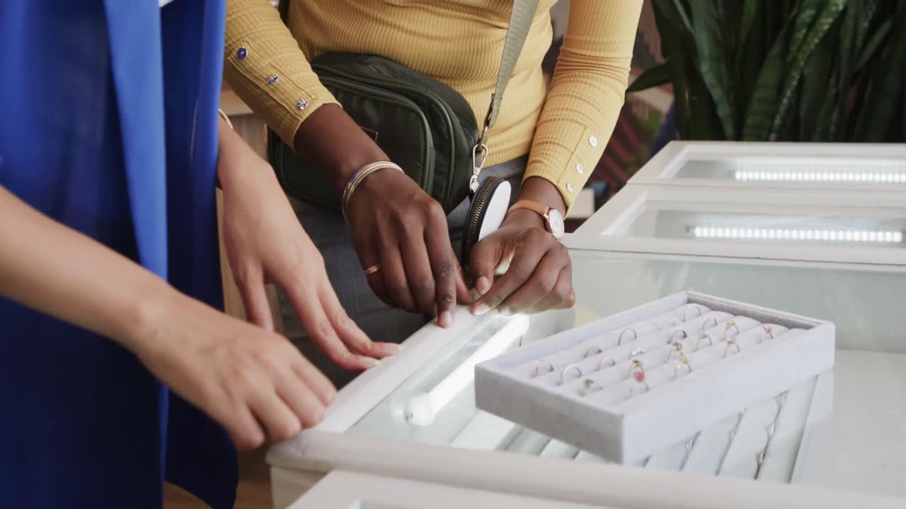 Diverse happy women choosing ring in jewellery shop in slow motion