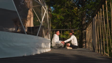 hombre medita con entrenador de yoga en glamping. hombre practica meditación bajo el control profesional de una instructora femenina en un eco-resort. fin de semana saludable