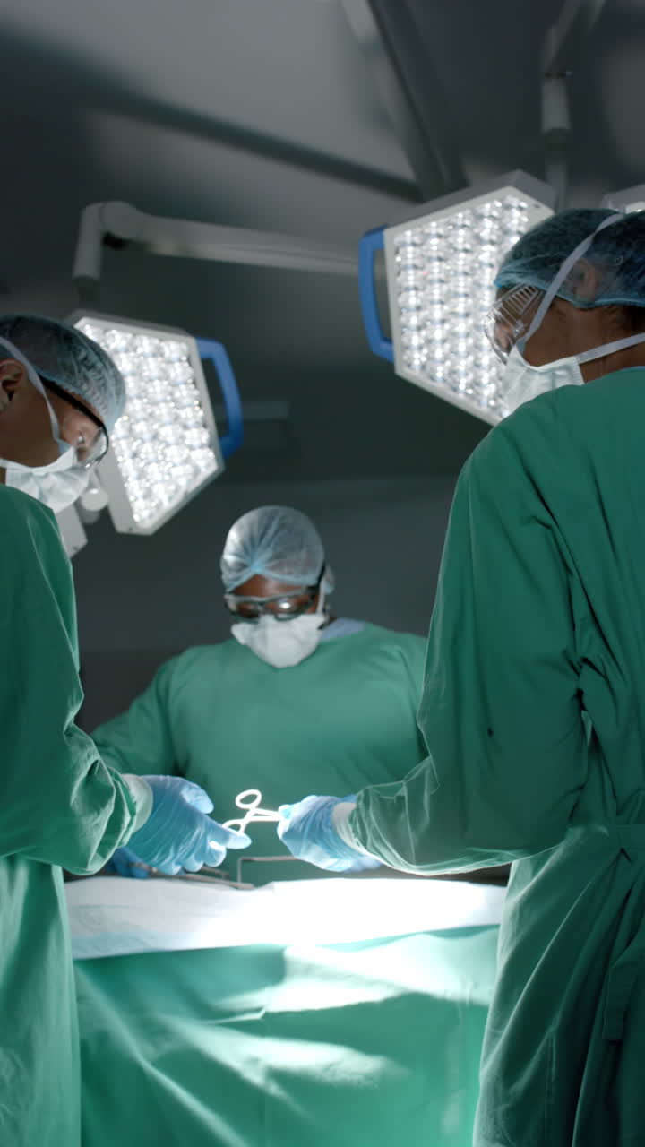 Vertical video of diverse surgeons with face masks during surgery in slow motion
