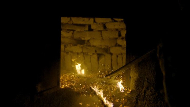 Ceneri di fuoco con scintille che cadono a terra. Il forno in argilla deve raggiungere la temperatura per cuocere la pizza. Dopo averlo riscaldato, i frammenti di legno vengono rimossi e il calore rimane nel forno in argilla.