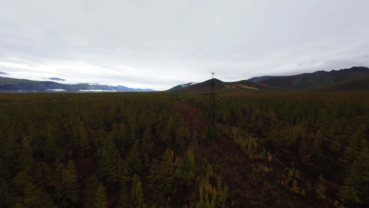 Bir drone, el değmemiş ormanlar ve dağ manzaraları arasından geçen elektrik iletim hatlarını sergileyerek Yakutistan'ın nefes kesen genişliğini görüntülüyor.