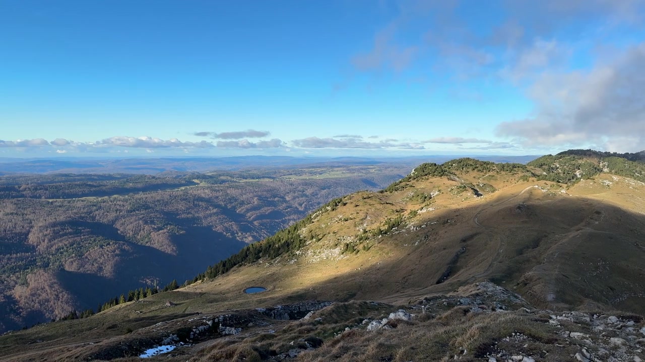 Panoramaudsigt over Jura-bjergenes landskab på en solrig dag. Langsom panorering mod venstre