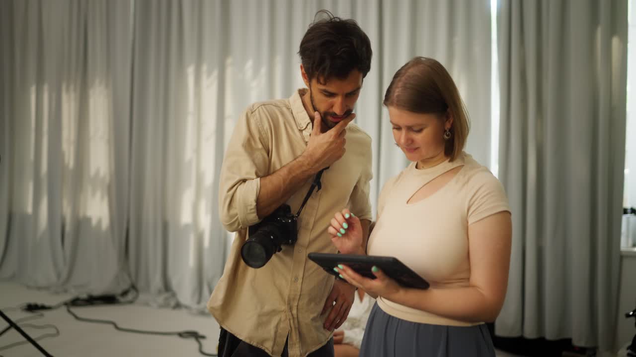 fotógrafo y modelo revisando fotos en una tableta durante una sesión de fotos