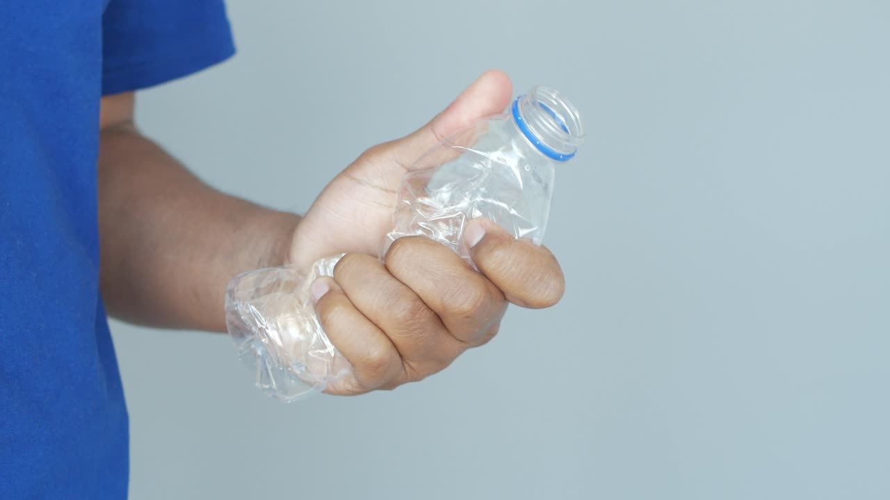 Person holding a crumpled plastic bottle