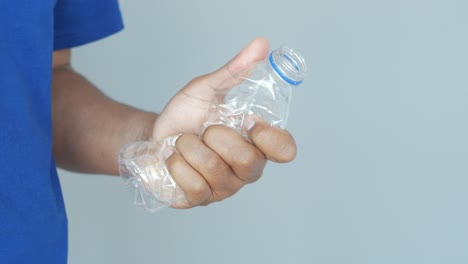 person holding a crumpled plastic bottle