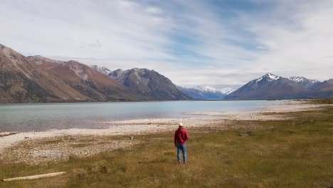 Person-from-behind-walking-towards-beautiful-glacier-lake-in-front-of-picturesque,-alpine-scenery