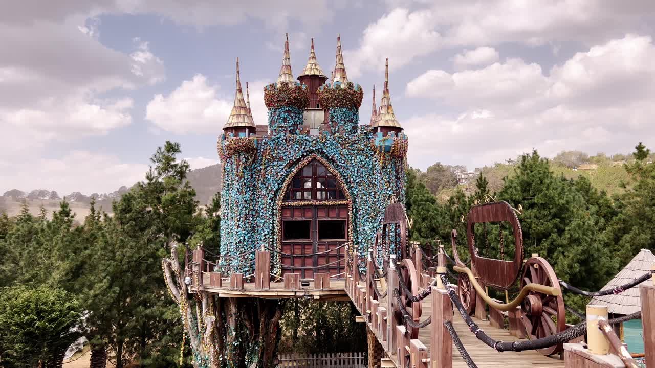 Fairy-tale castle, ornate towers, wooden bridge is hidden among lush green trees