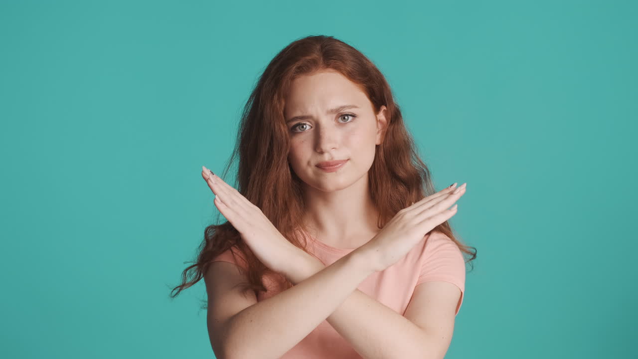 은 머리의 소녀가 르키즈색 배경에서 카메라를 보고 있습니다.