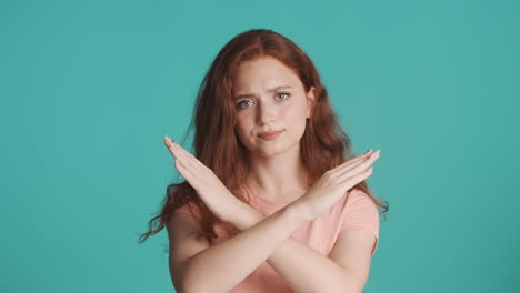 Redheaded-girl-looking-at-camera-on-turquoise-background.