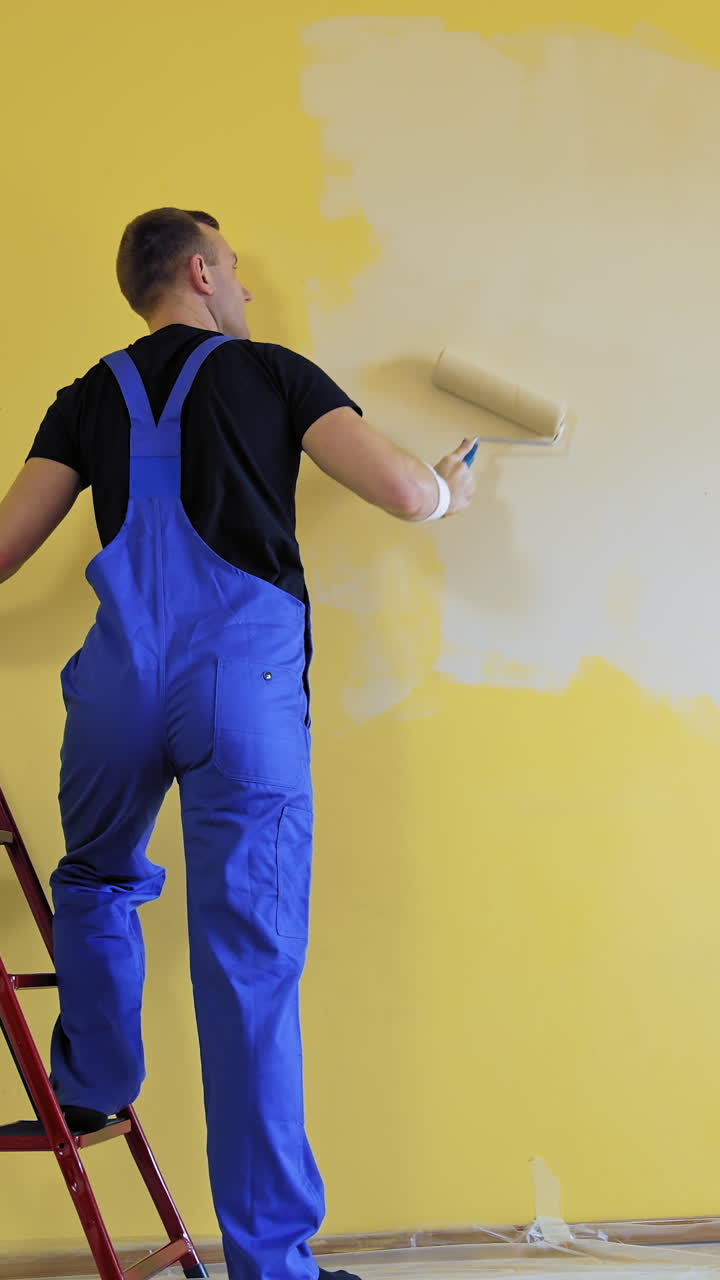 Builder with paint roller. Building contractor painting wall with roller brush