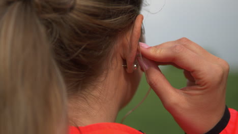 close up, back of blonde caucasian runner woman's head putting on earphones