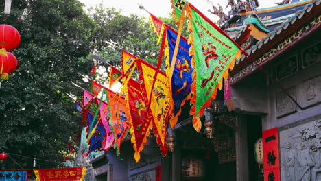 Chinese-flag-banners-hanging-in-front-of-the-gate-of-an-Asian-pagoda,-with-a-view-of-the-pagoda