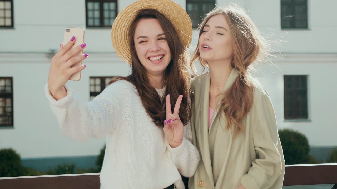 두 친구가 야외에서 셀피를 찍고 있다