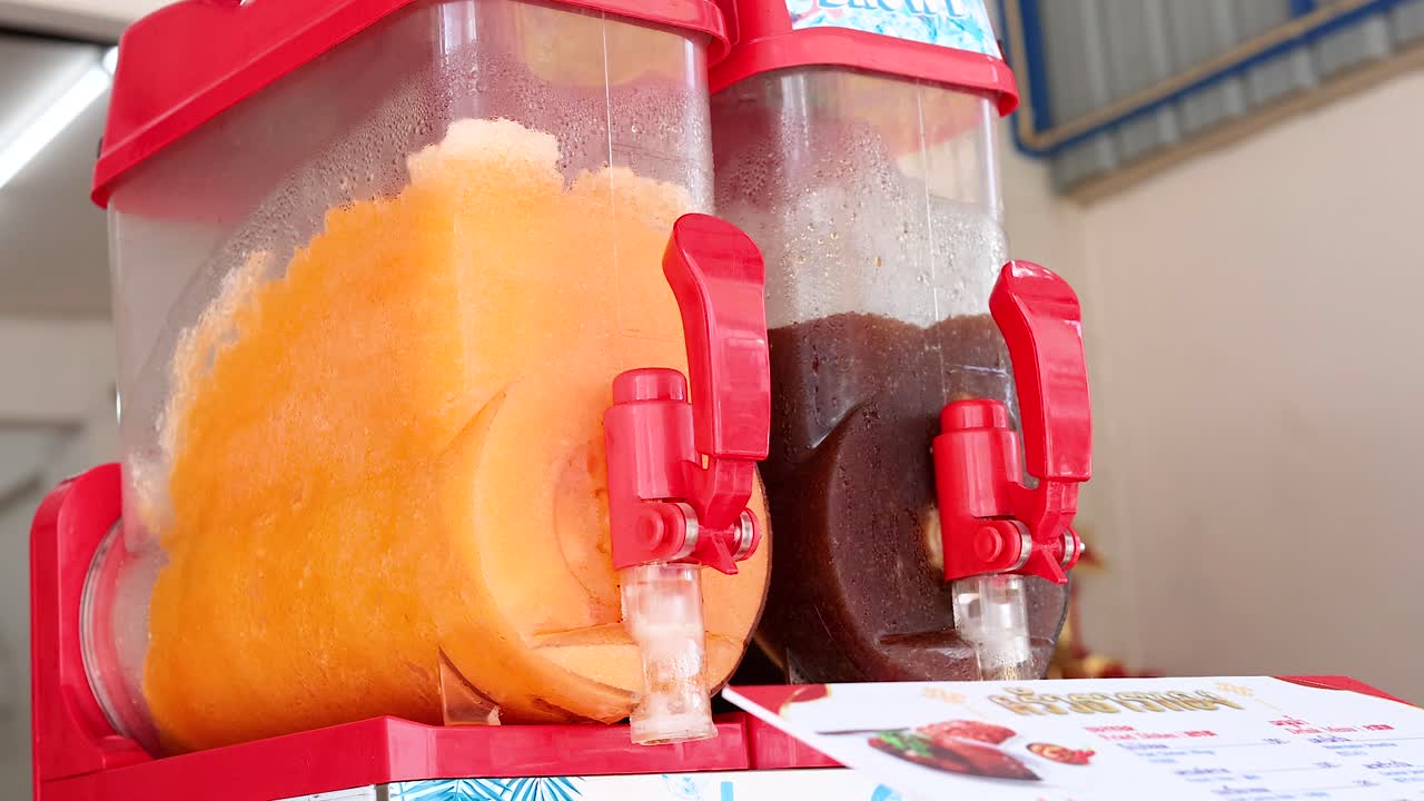 Brightly colored slushy machines in a Phuket market setting, showcasing vibrant orange and red hues under natural lighting