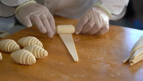 a french pastry chef rolls out croissant dough on the table