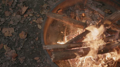 slow motion footage of a fire with the camera panning across the flames on top of a fire ring at a campground