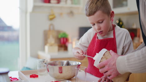 little boy helps dad in the kitchen and pours flour into the dough