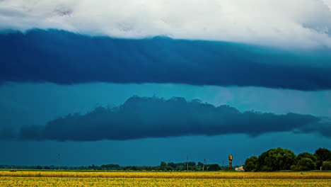 Der-Zeitraffer-Zeigt-Den-Sich-Ständig-Verändernden-Himmel-Mit-Wolken,-Die-Inmitten-Des-Wechselnden-Blauen-Lichts-über-Dem-Gelben-Ackerland-Lettlands-Verschmelzen