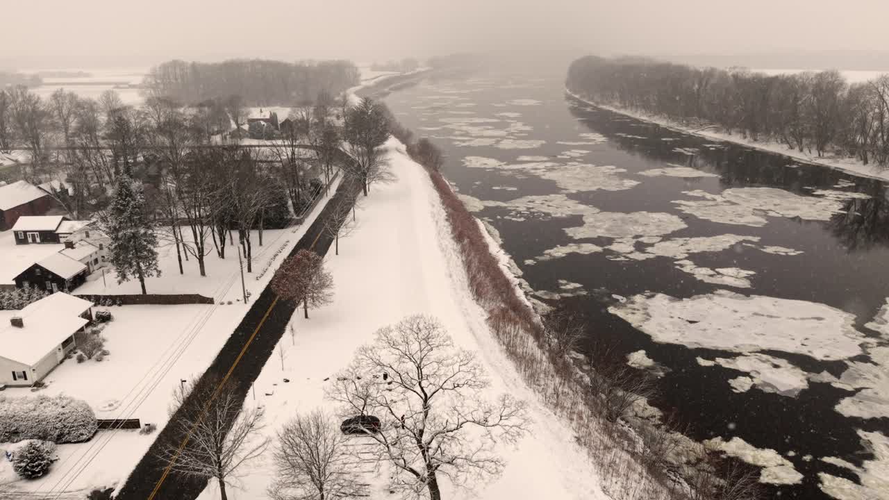 Ripresa aerea di una città innevata con neve che cade vicino a un fiume.