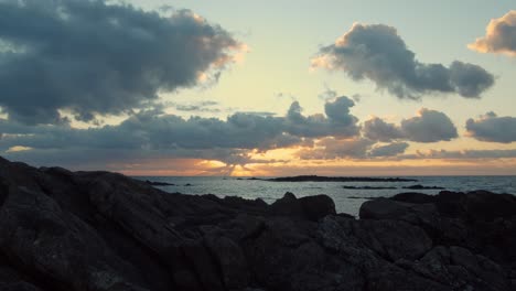 motion timelapse of clouds moving above rocky ocean on a sunset - wide shot