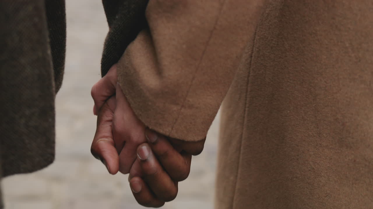 Close-up view of African American man and caucasian woman holding hands and walking on the street