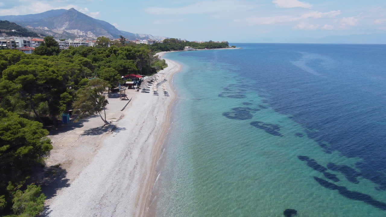 A drone flies parallel to the beach above the small town of Xylokastro in Greece