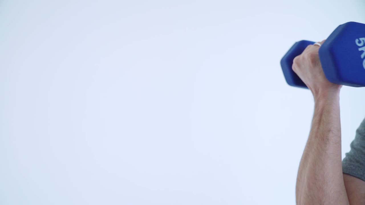 5kg 덤벨을 하 배경에서 느린 동작으로 들어 올리는 팔