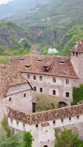 vertical shot above roncolo castle’s stone walls, revealing its medieval structure and green surroundings