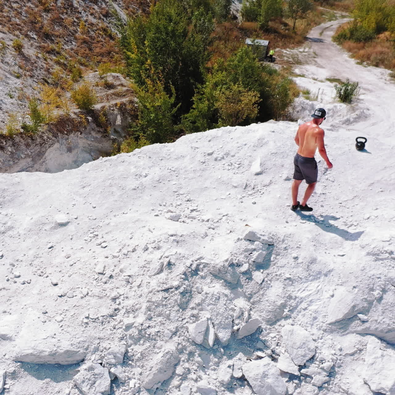 Brutal strong bodybuilder posing outdoor. Photoshoot in a quarry. Outdoor sports concept. Aerial view. Handsome strongman walks up a quarry. White landscape.