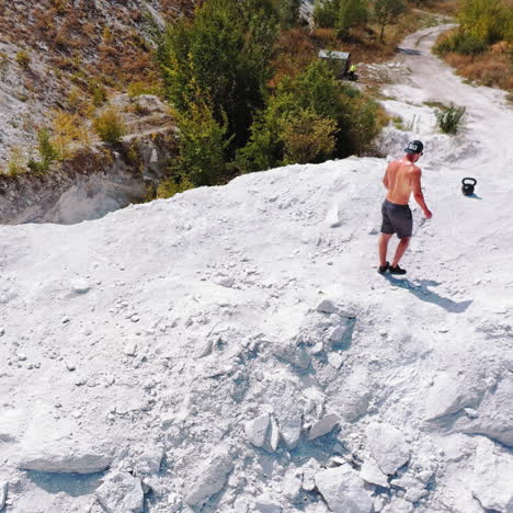 brutal strong bodybuilder posing outdoor. photoshoot in a quarry. outdoor sports concept. aerial view. handsome strongman walks up a quarry. white landscape.