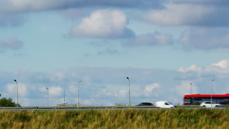 coches rápidos y autobuses conduciendo en una autopista bajo un cielo nublado