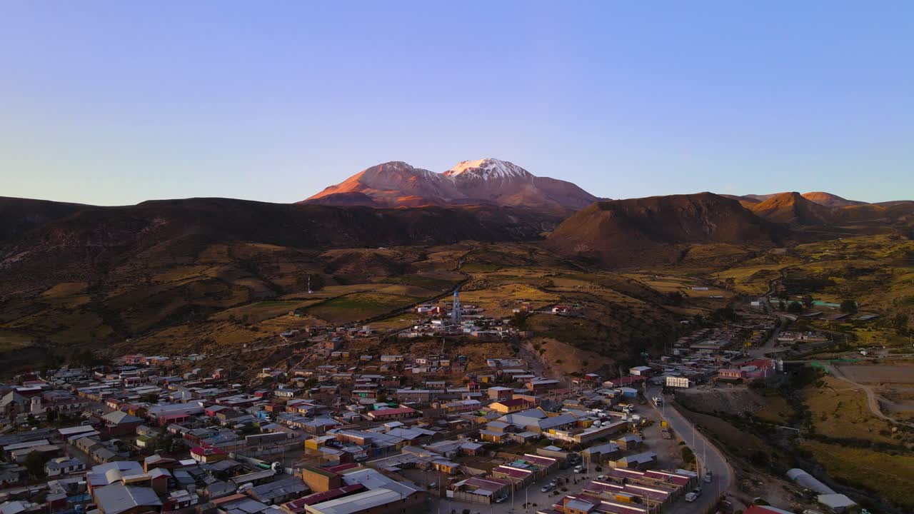 Drone shot flying over the small town of Putre in Chile at an altitude of 3650 meters with the Taapac&aacute; volcano in the background at sunset