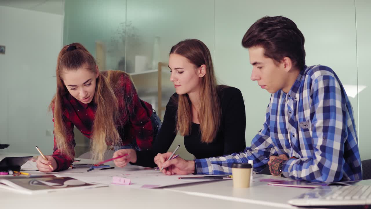 equipo de negocios creativo de tres personas que se reúnen en una oficina moderna y discuten ideas de negocios mientras se sientan a la mesa. jóvenes profesionales haciendo bocetos y preparando su nuevo proyecto