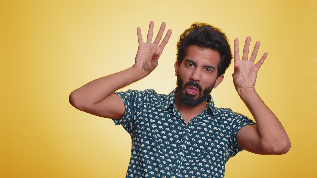 Comical funny indian man making playful silly facial expressions fooling around showing tongue