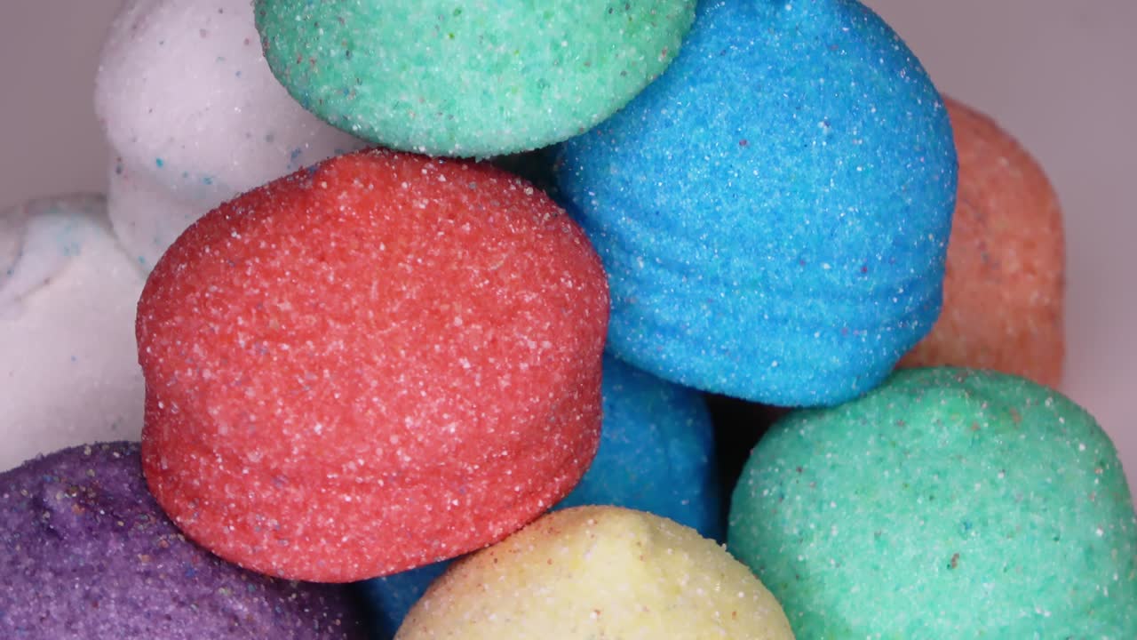 dulces de malvavisco muy coloridos en un fondo blanco girando en círculo - imágenes en bucle.