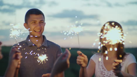 amigos con fuegos artificiales en las manos divirtiéndose en una fiesta por la noche