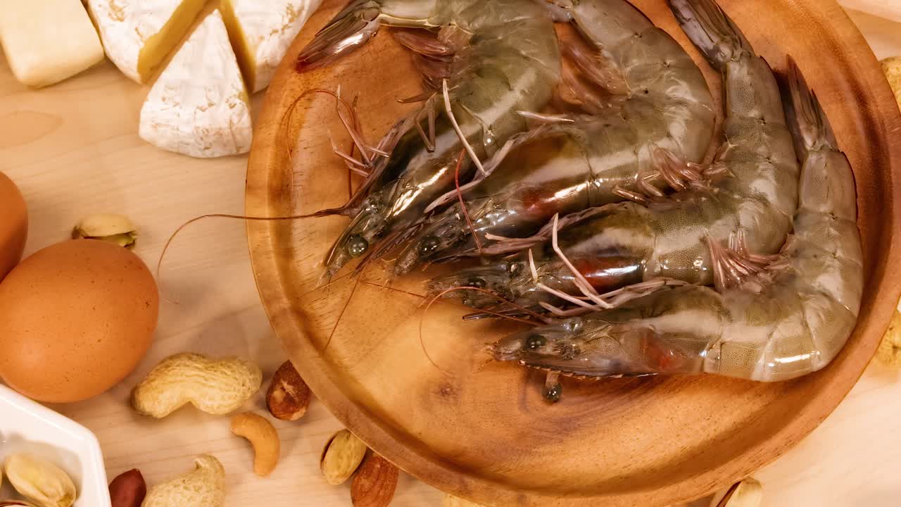 Close-up view of shrimp, eggs, and cheese arranged on a wooden surface.