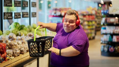 a happy and cheerful overweight man in a purple t-shirt and red headphones walks through the supermarket and dances with a basket in his hands, choosing fruits for himself. a man tosses an apple and puts it in his basket