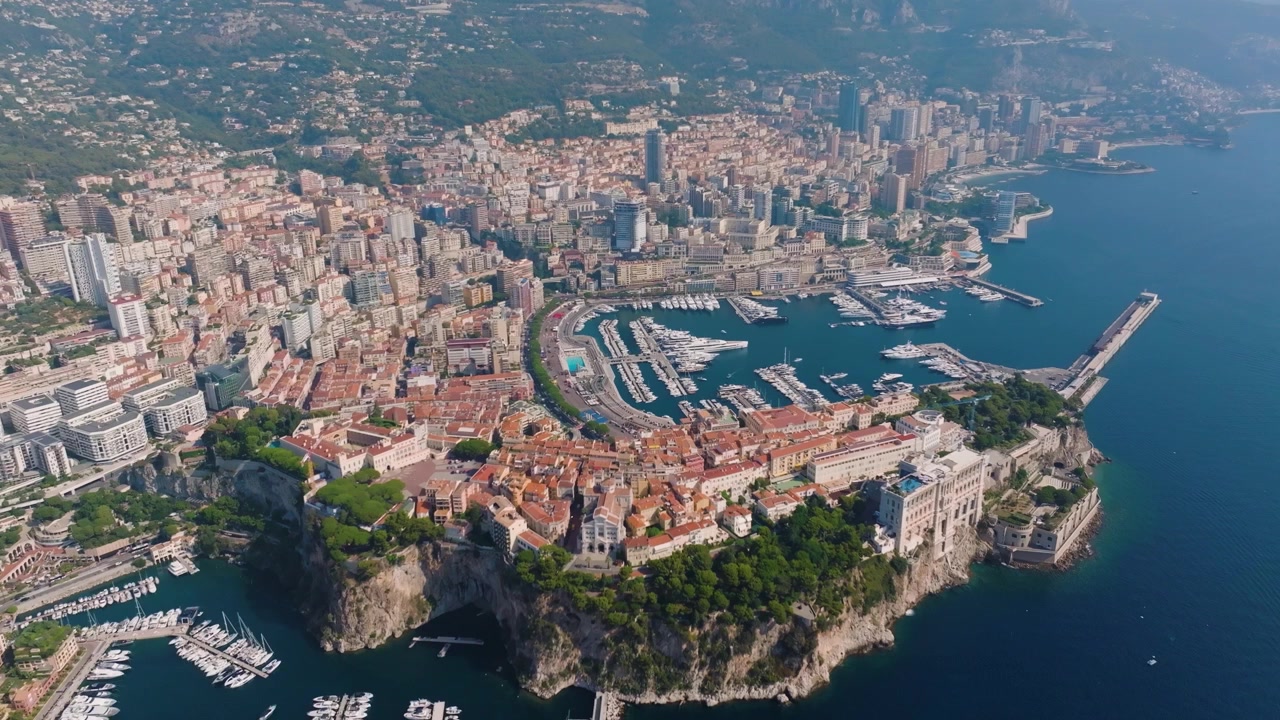 Una veduta aerea di Monaco che mostra la costa, gli edifici della città e gli yacht. La vivace attività intorno al porto evidenzia la disposizione urbana e le caratteristiche naturali della zona