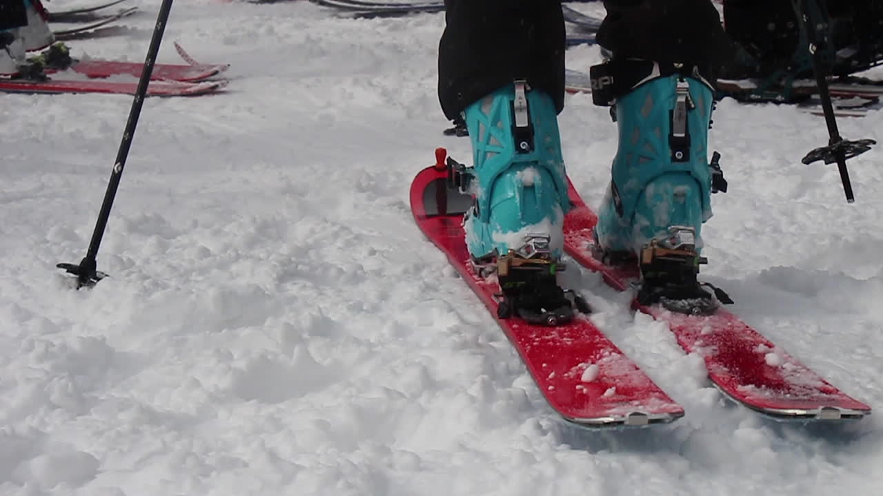 person stepping into skies with ski boots and poles