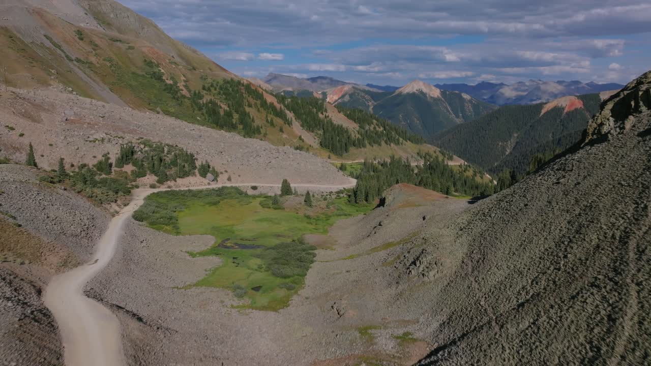 Biler på Ophir Pass, vej langs klippesiden til åbent alpint terræn, den ikoniske bjergroutes barske karakter, dolly-optagelse fra luften